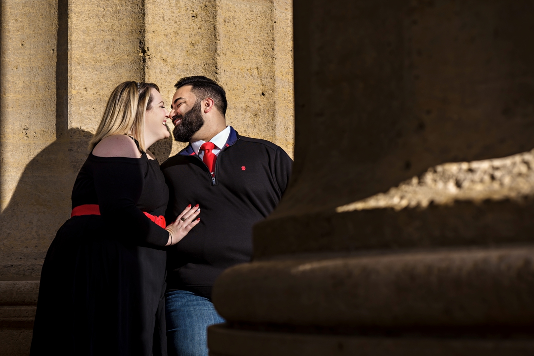 A woman leans in to kiss her fiance in between the columns of the Philadelphia museum of art.